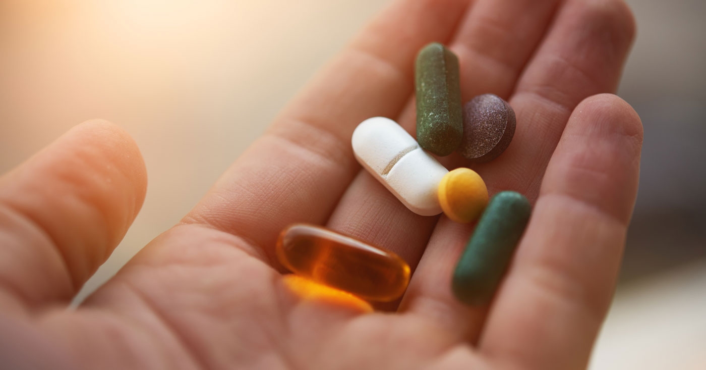 Hand holding supplements and vitamins.