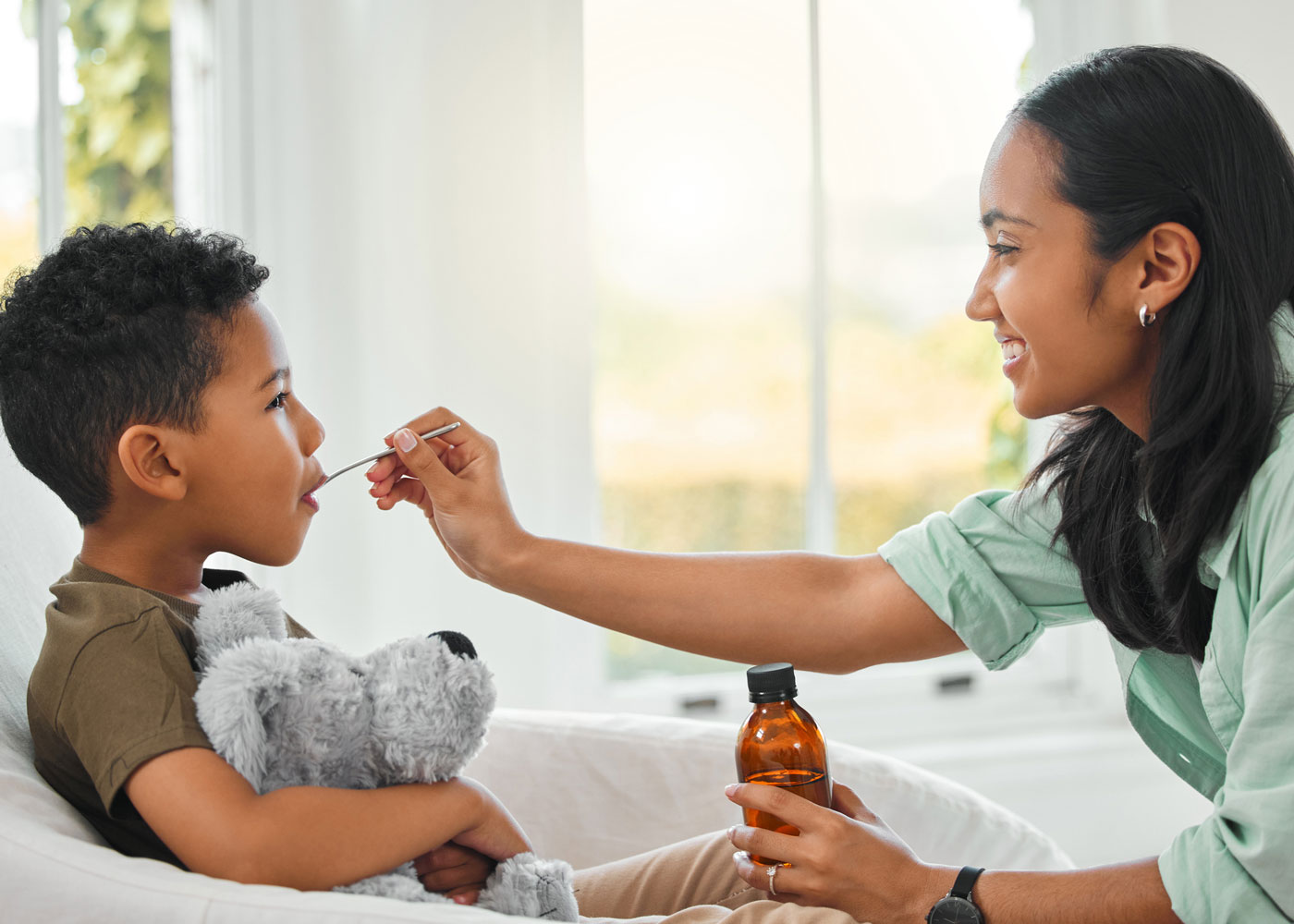 Mom giving son medicine.