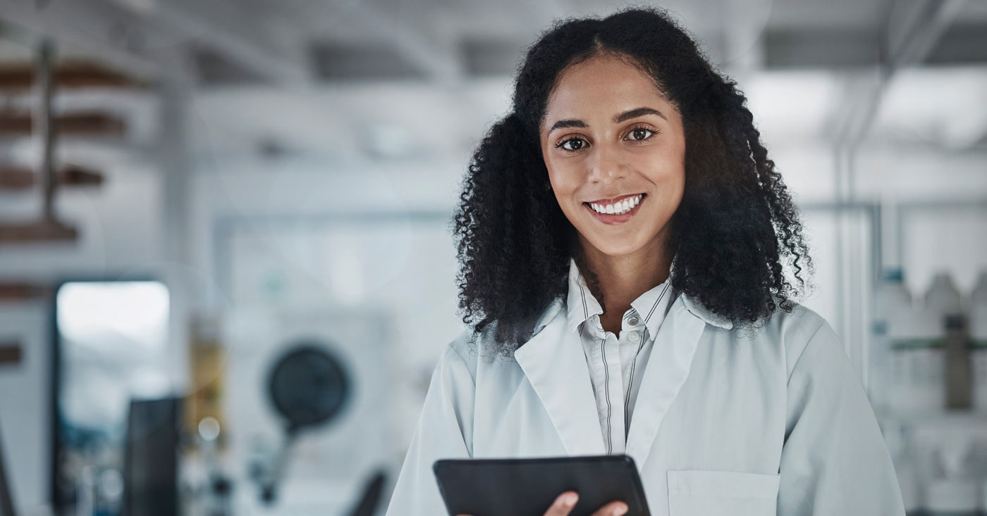 Lab worker with tablet smiling at camera.